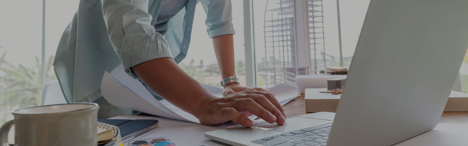 Mensch arbeitet mit Laptop und Plänen Mensch arbeitet mit Laptop und Plänen